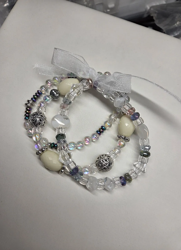 Elegant beaded bracelets with a delicate bow, featuring pearls and crystals.