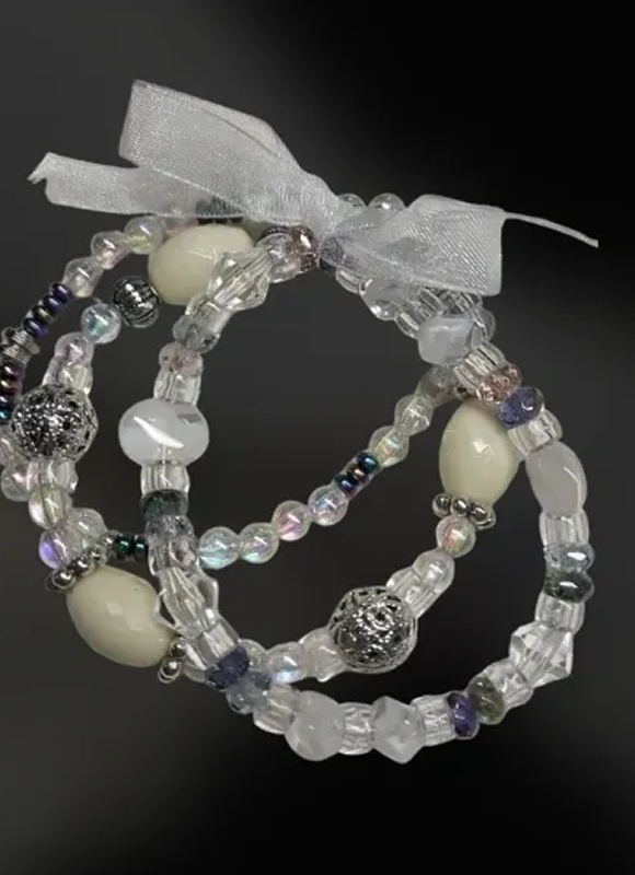 Three beaded bracelets with white and iridescent beads tied with a sheer ribbon.