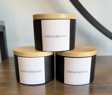 Three Joshua Michael candles with wooden lids arranged in a pyramid.